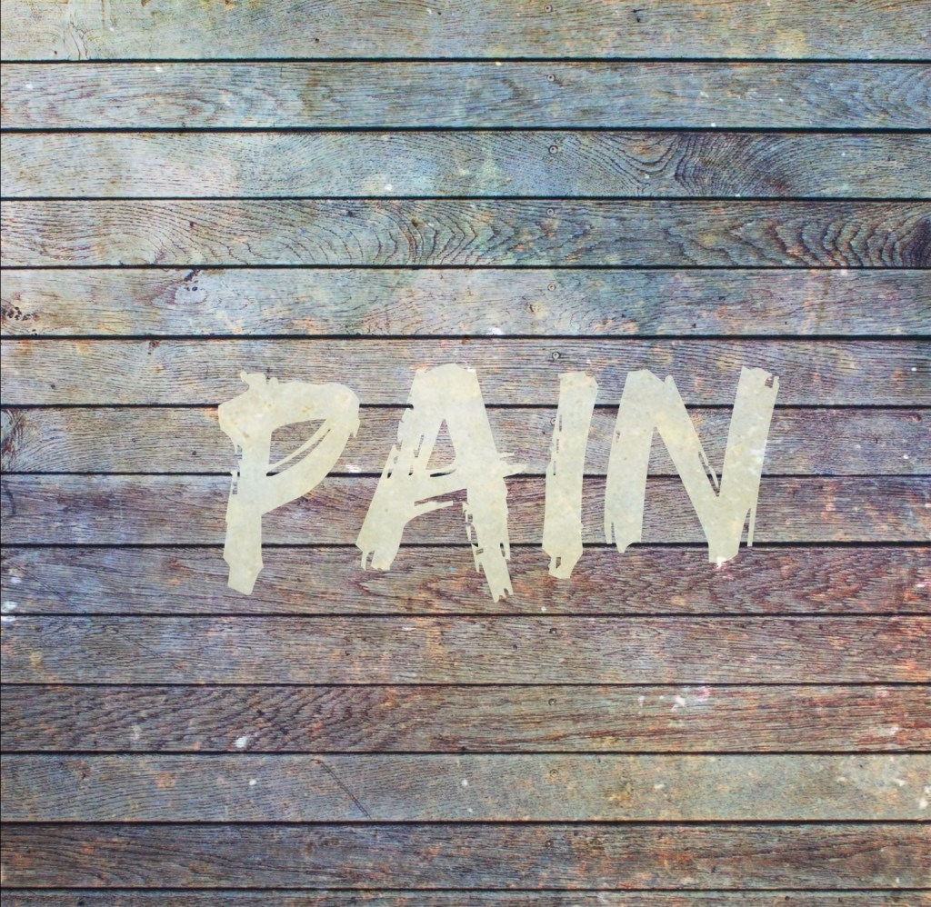 Board wall, distressed. “PAIN” painted on top in white. 